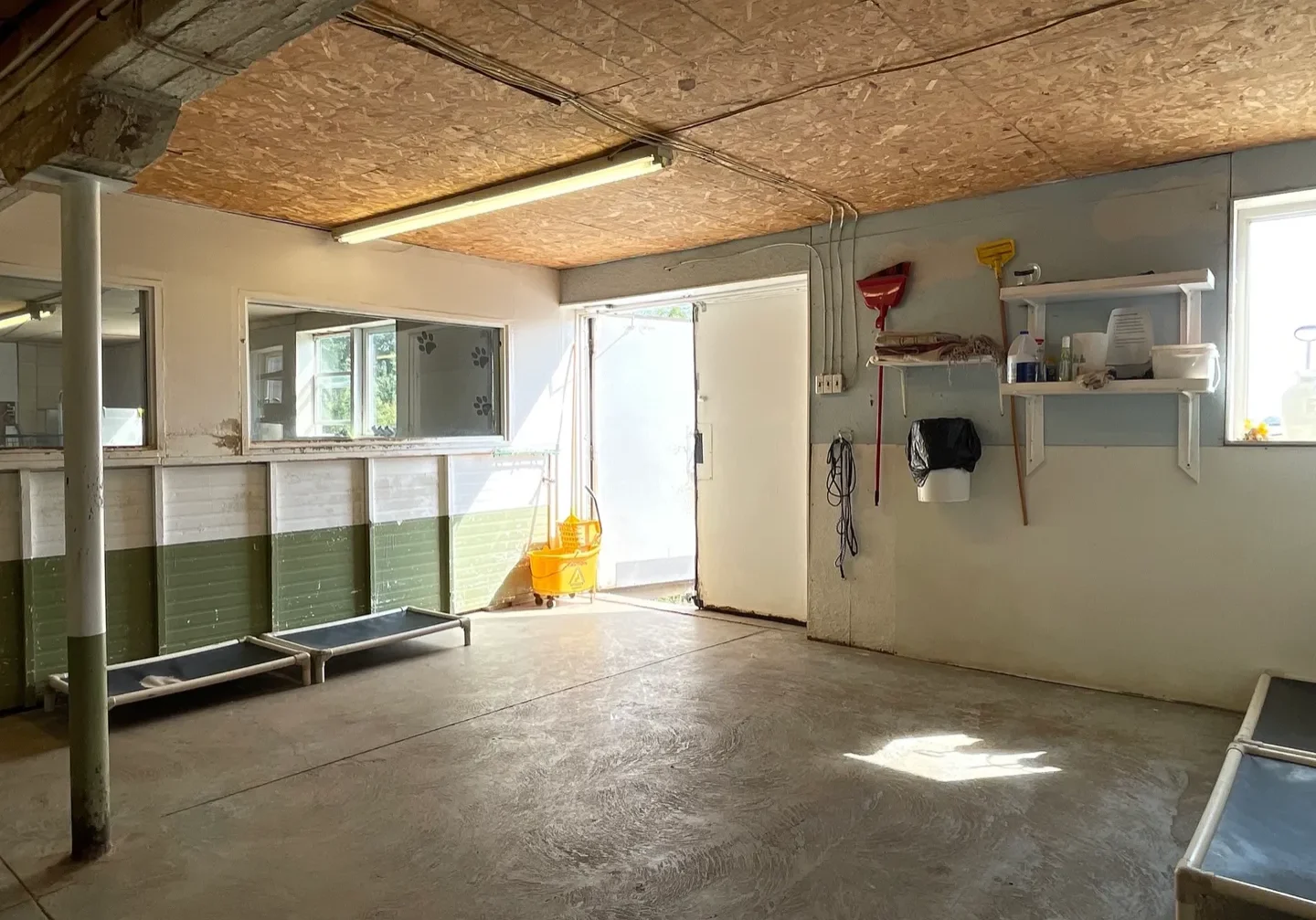 A garage with a door open and shelves in the corner.